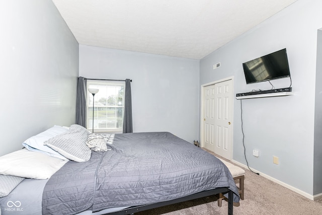 bedroom with a closet, visible vents, light colored carpet, and baseboards