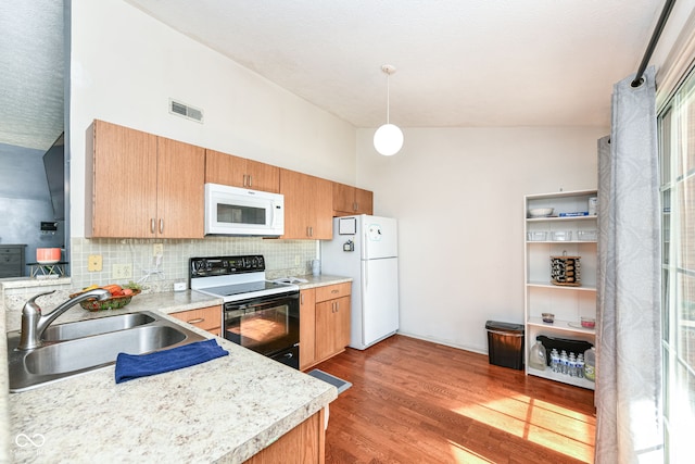 kitchen with light countertops, a sink, backsplash, and white appliances