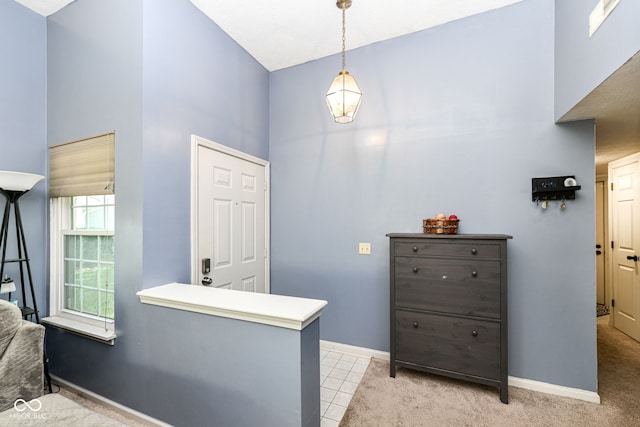 interior space featuring baseboards, light tile patterned floors, and a high ceiling