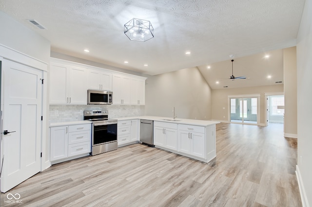 kitchen featuring ceiling fan, white cabinets, kitchen peninsula, stainless steel appliances, and light hardwood / wood-style floors