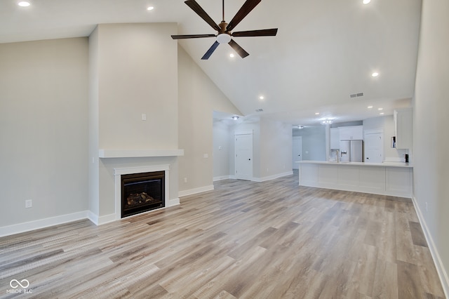 unfurnished living room with light wood-type flooring, high vaulted ceiling, and ceiling fan