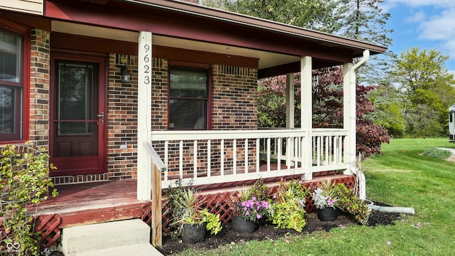 doorway to property featuring covered porch and a lawn