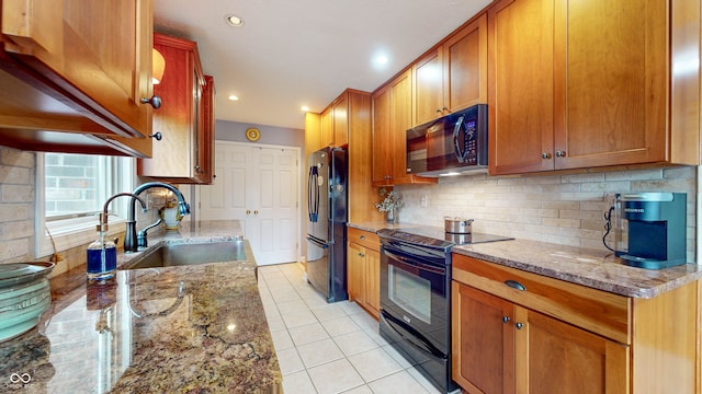 kitchen with tasteful backsplash, sink, black appliances, and light stone countertops