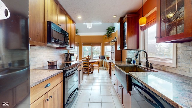 kitchen featuring sink, hanging light fixtures, black appliances, light tile patterned flooring, and decorative backsplash