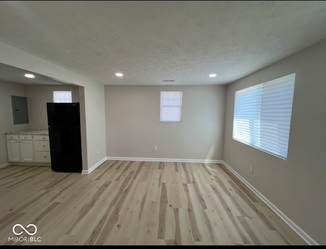 spare room with electric panel, light hardwood / wood-style flooring, and a textured ceiling