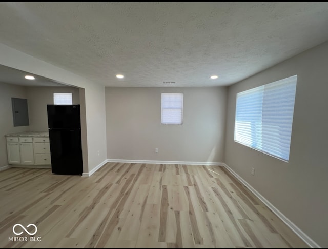 unfurnished room with a textured ceiling and light wood-type flooring