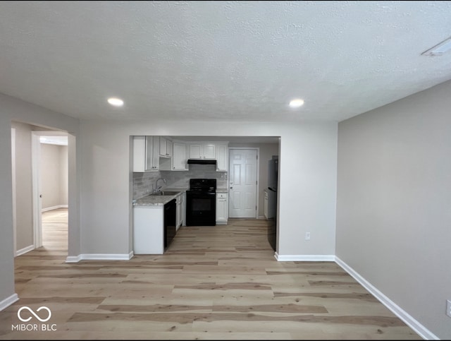 kitchen with light hardwood / wood-style floors, sink, backsplash, black appliances, and a textured ceiling