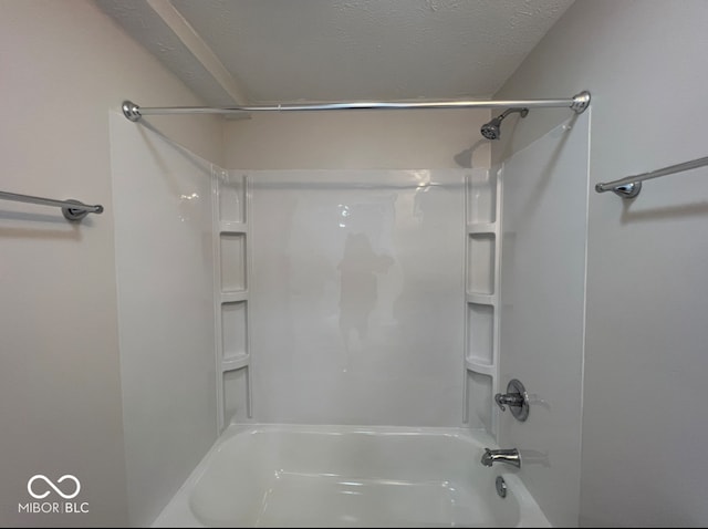 bathroom with washtub / shower combination and a textured ceiling