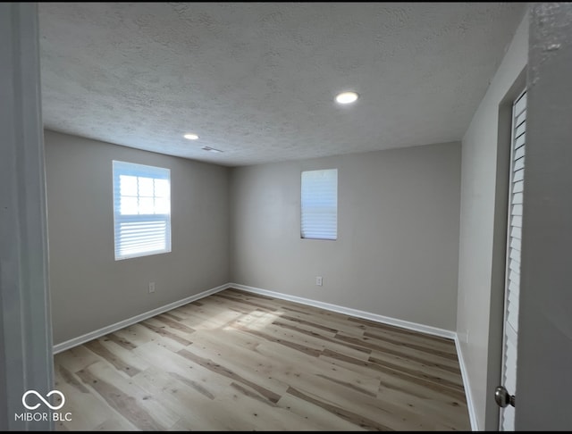 empty room with a textured ceiling and light wood-type flooring