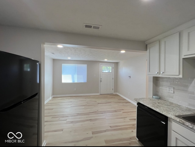 kitchen with light stone counters, white cabinets, black appliances, light wood-type flooring, and decorative backsplash