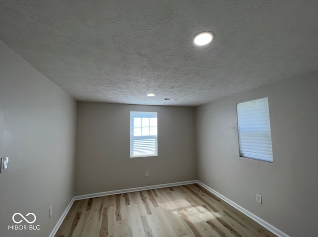 spare room featuring light hardwood / wood-style flooring and a textured ceiling