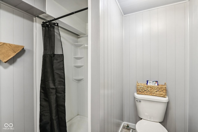 bathroom with toilet, a shower with curtain, and wooden walls