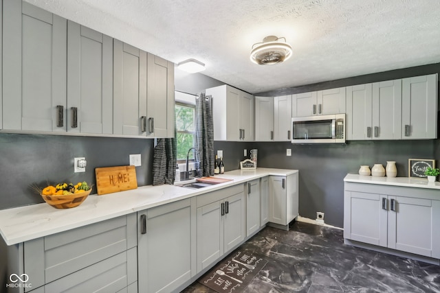 kitchen featuring gray cabinetry, a textured ceiling, and sink