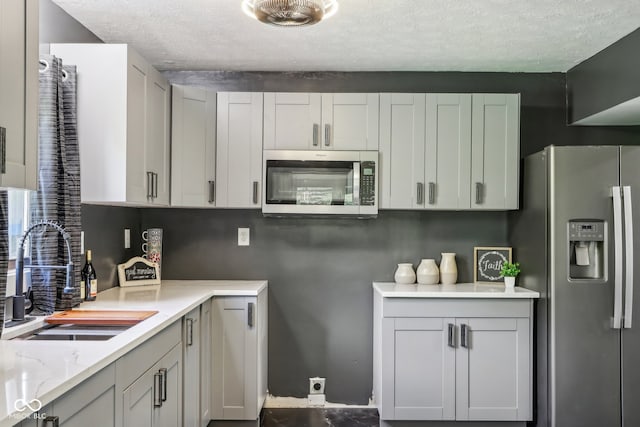 kitchen with appliances with stainless steel finishes, a textured ceiling, and sink