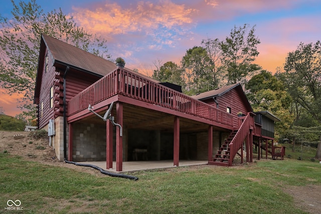 back house at dusk featuring a patio, a deck, and a yard