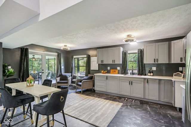 kitchen with gray cabinetry, a textured ceiling, plenty of natural light, and french doors