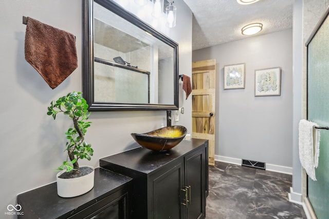 bathroom with vanity, a textured ceiling, and an enclosed shower