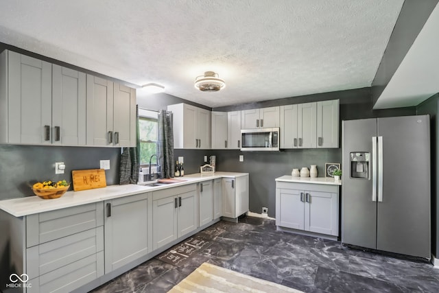 kitchen featuring gray cabinets, sink, a textured ceiling, and stainless steel appliances