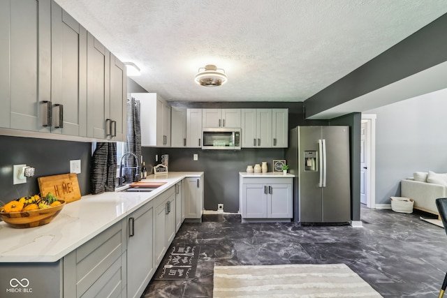 kitchen with gray cabinetry, appliances with stainless steel finishes, a textured ceiling, and sink