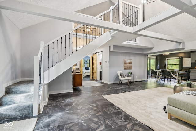 interior space with a textured ceiling, a barn door, and beamed ceiling