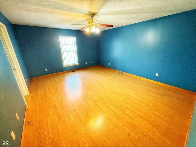 unfurnished room with a textured ceiling, wood-type flooring, and ceiling fan