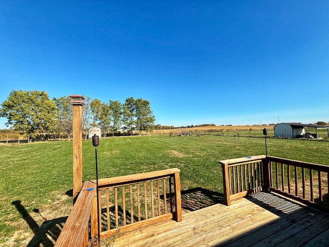 wooden deck featuring a rural view, a storage unit, and a lawn