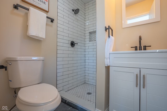 bathroom with vanity, tiled shower, and toilet