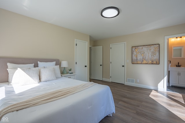 bedroom with ensuite bath, wood-type flooring, and sink