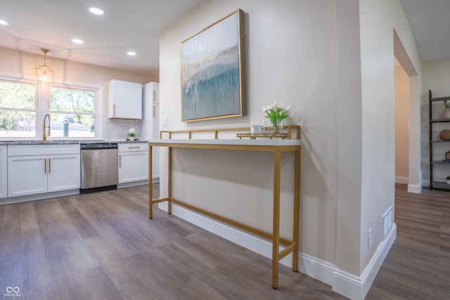 kitchen featuring stainless steel dishwasher, white cabinetry, decorative light fixtures, and hardwood / wood-style flooring