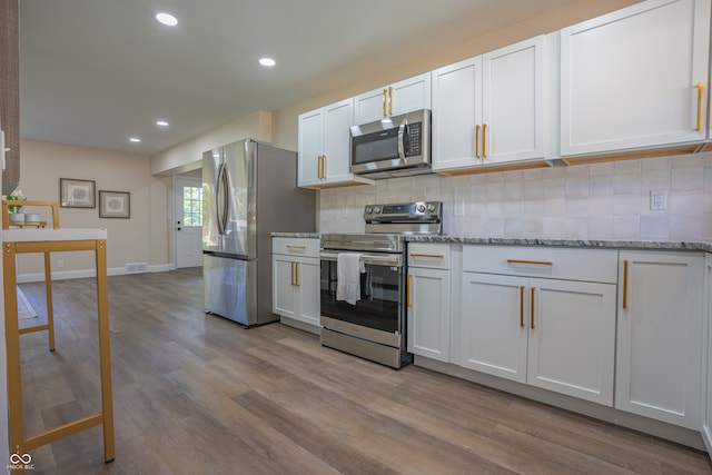 kitchen with white cabinets, stainless steel appliances, light wood-type flooring, and tasteful backsplash