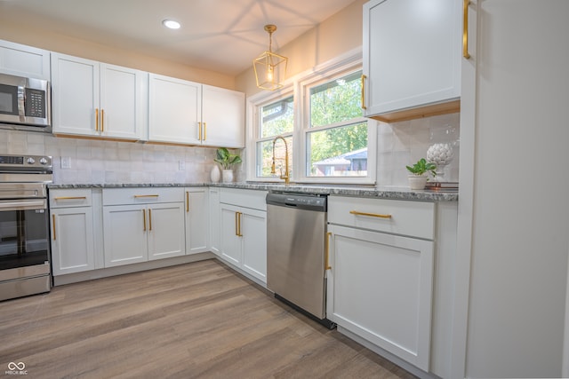 kitchen with appliances with stainless steel finishes, light hardwood / wood-style flooring, pendant lighting, and white cabinets