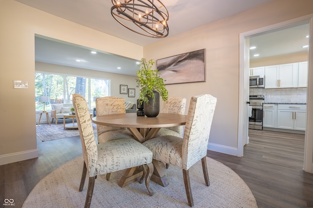 dining space featuring dark wood-type flooring and an inviting chandelier