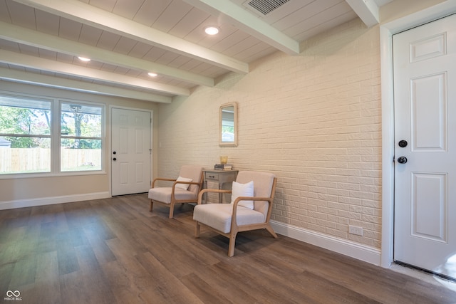 living area with beamed ceiling, dark wood-type flooring, and brick wall