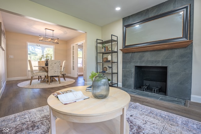 living room featuring a tiled fireplace, hardwood / wood-style flooring, and an inviting chandelier