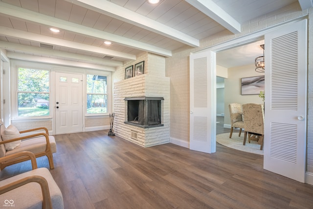 living room with beam ceiling, brick wall, a fireplace, and dark hardwood / wood-style floors