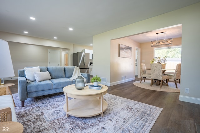 living room with dark wood-type flooring and a chandelier