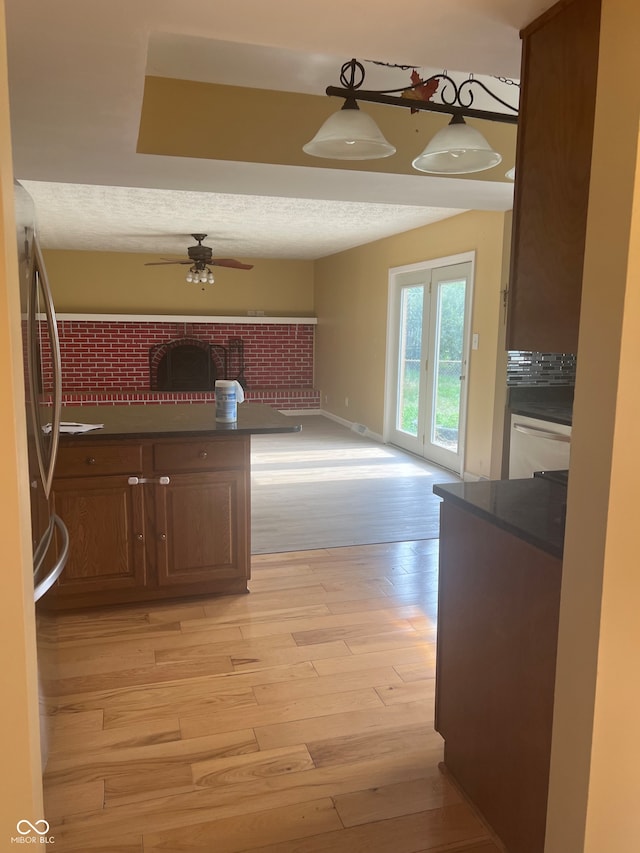 kitchen with ceiling fan, pendant lighting, kitchen peninsula, a textured ceiling, and light hardwood / wood-style floors