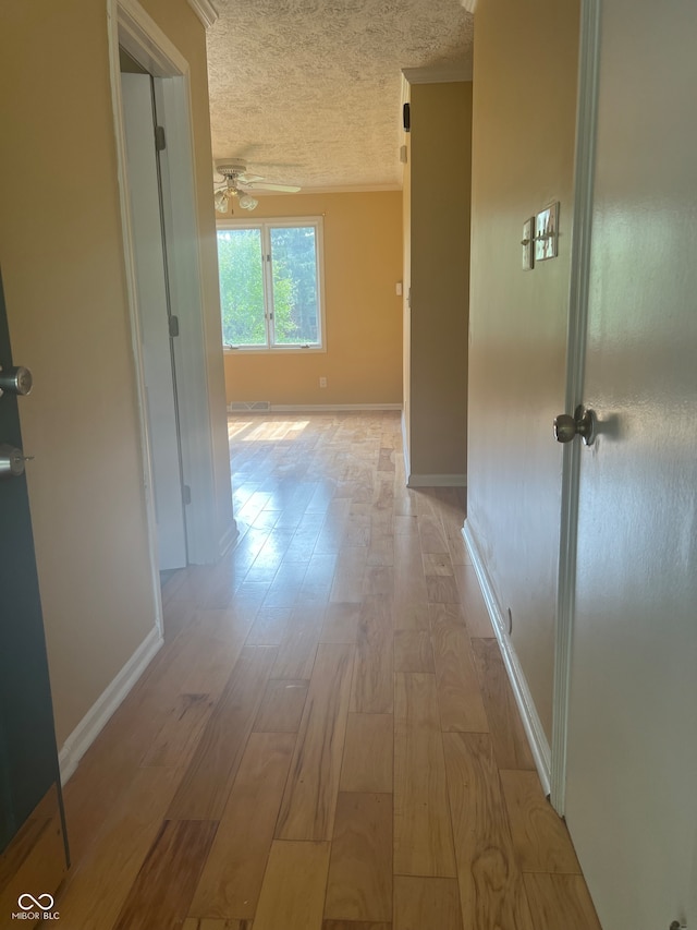 hallway with light hardwood / wood-style floors and a textured ceiling