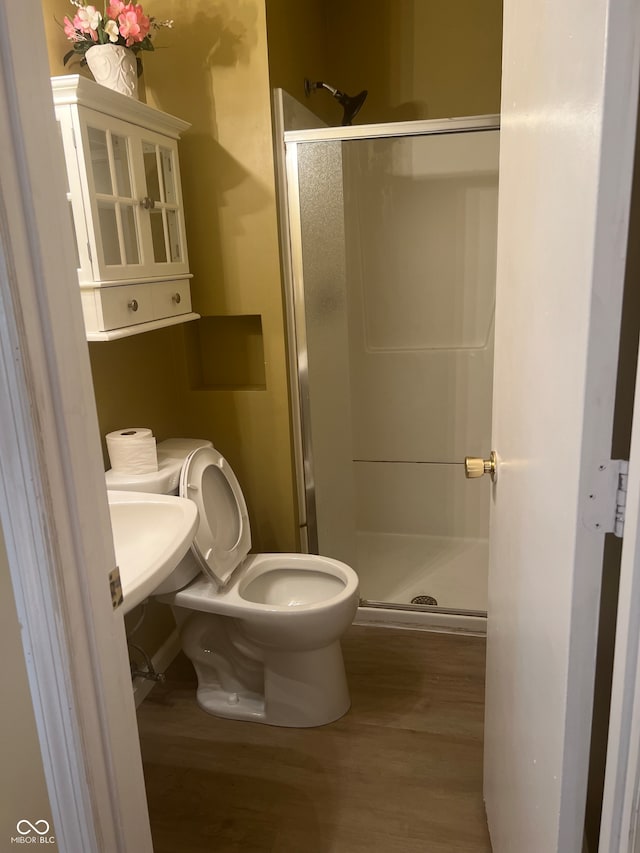 bathroom with hardwood / wood-style floors, sink, a shower with door, and toilet