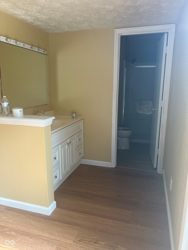 bathroom with toilet, vanity, wood-type flooring, and a textured ceiling