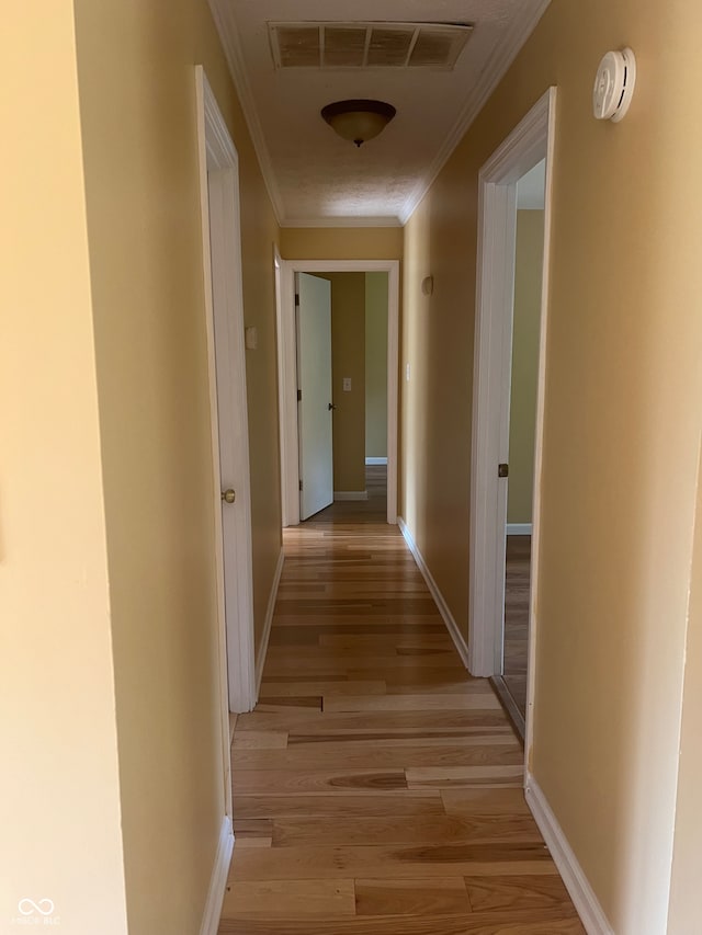 hall with ornamental molding and light hardwood / wood-style flooring