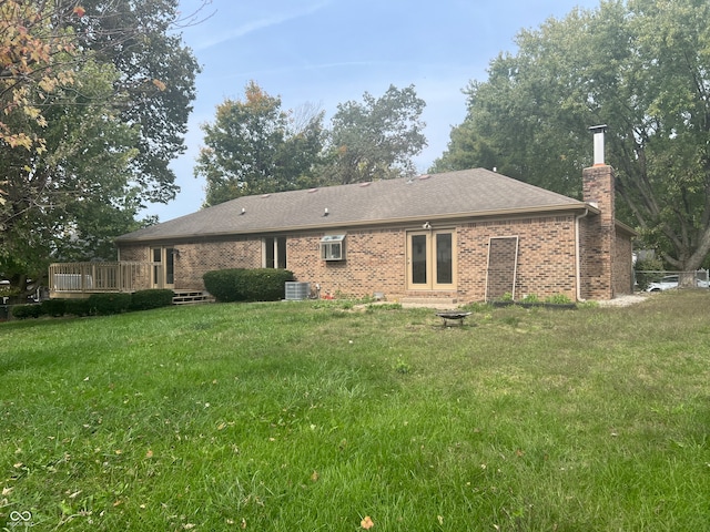 rear view of house with central AC unit, a deck, and a yard