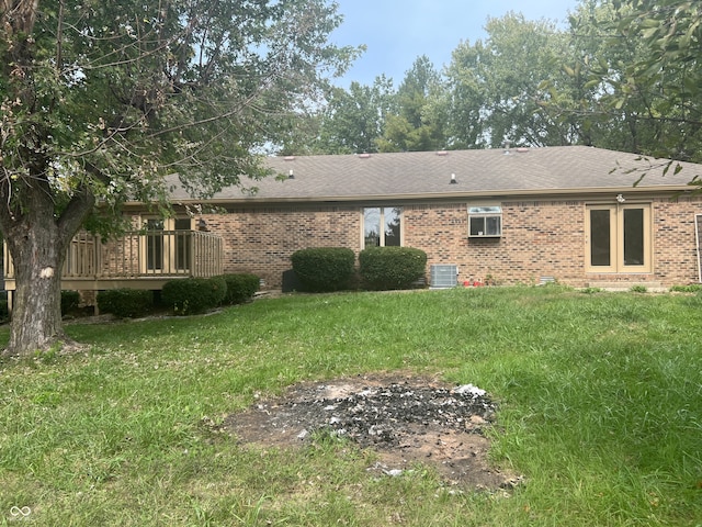 rear view of property with cooling unit, a deck, and a yard