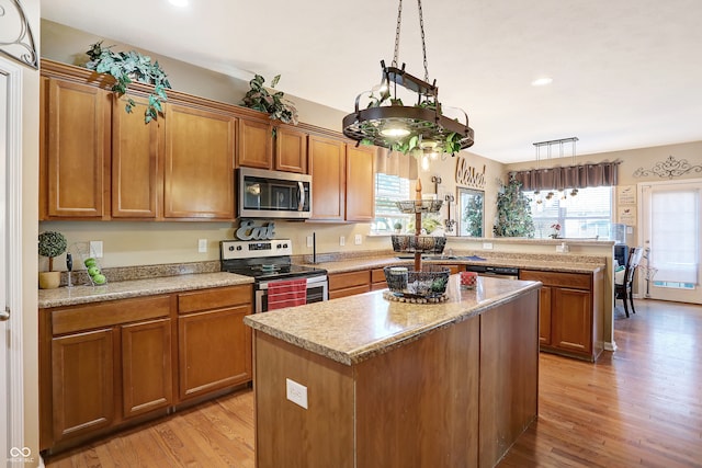 kitchen featuring light hardwood / wood-style floors, stainless steel appliances, pendant lighting, and a kitchen island