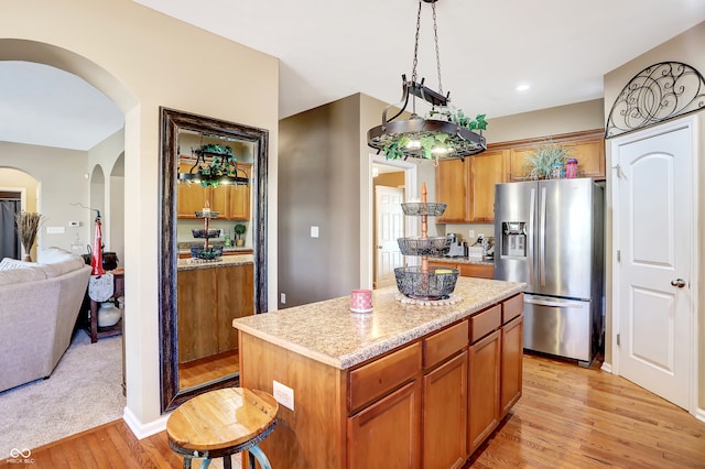 kitchen with hanging light fixtures, a center island, stainless steel refrigerator with ice dispenser, and light hardwood / wood-style floors