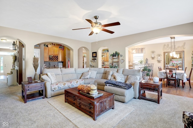 living room featuring light carpet, ceiling fan with notable chandelier, and plenty of natural light