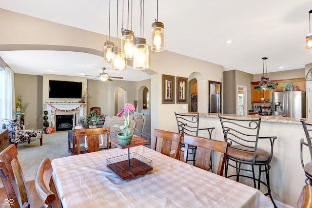 dining space with light carpet and ceiling fan