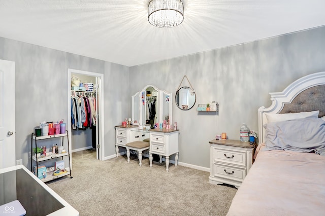 bedroom with a spacious closet, a notable chandelier, a closet, and light colored carpet