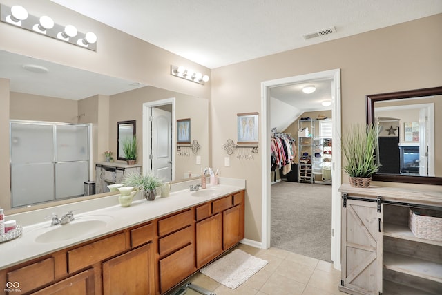 bathroom with vanity, a textured ceiling, tile patterned flooring, and an enclosed shower