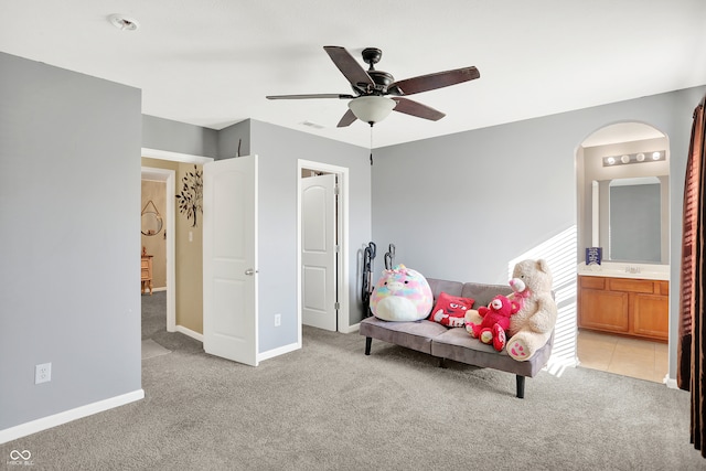 bedroom with ensuite bath, light colored carpet, and ceiling fan